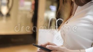 女人`手拿着智能手机在购物中心购物